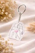 Keychain with a design of a couple hugging and a heart, on a soft fabric background.