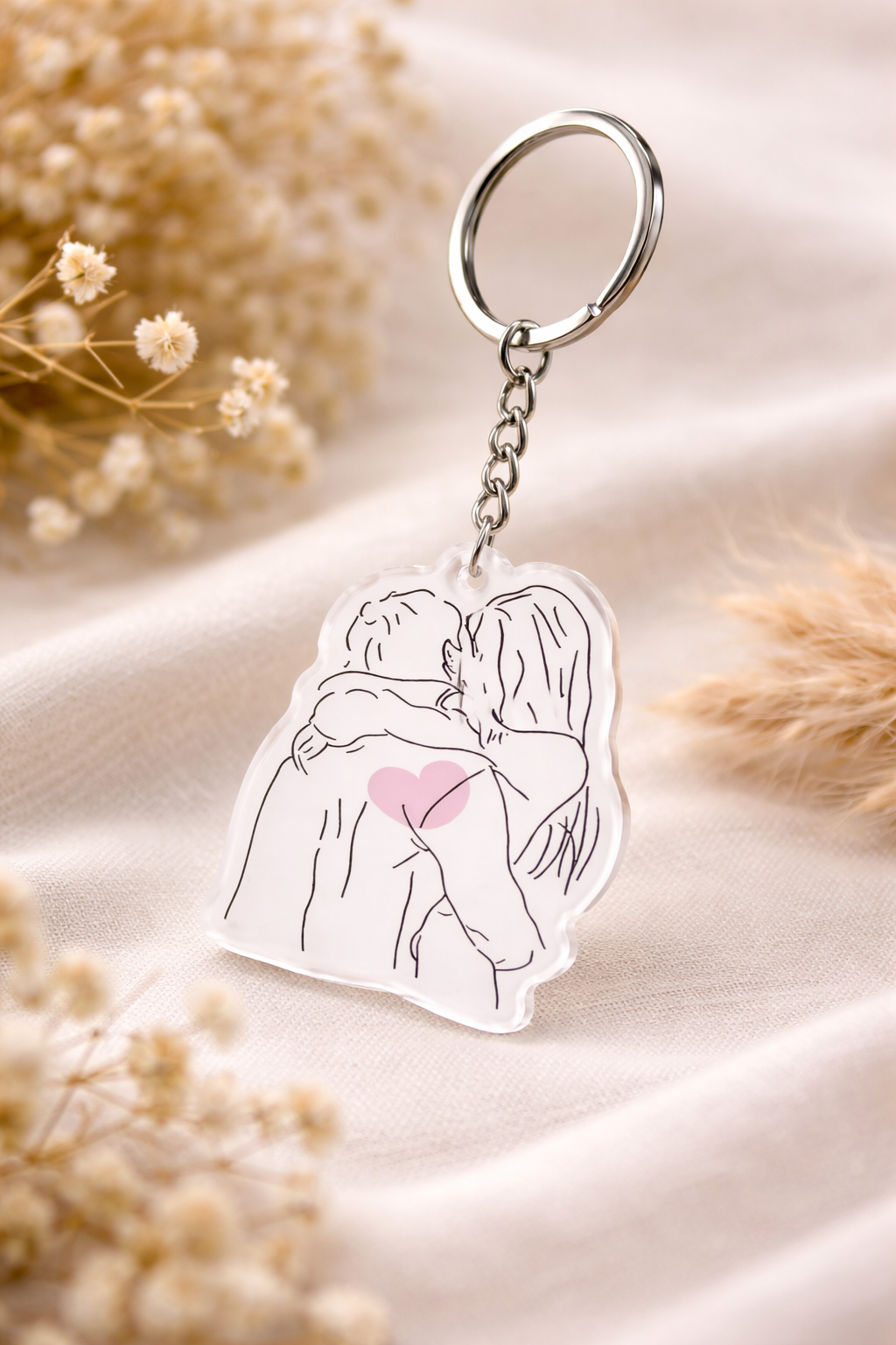 Keychain with a design of a couple hugging and a heart, on a soft fabric background.